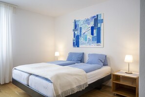 A bedroom with a bed, two bedside tables, and a wall-mounted abstract painting.