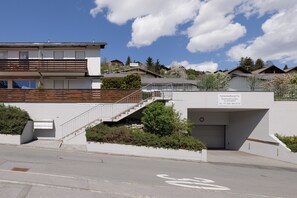 A modern building with a staircase leading to a garage. There is a sign indicating 'Ferienstiegung Trü' and a contact number.
