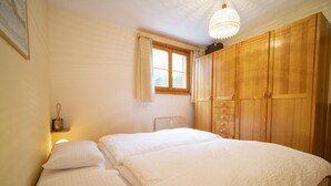 Une chambre avec un grand lit, une armoire en bois et une fenêtre avec des rideaux.