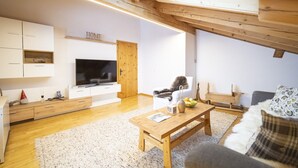 A modern living room with a TV, wooden furniture, a sofa, and a dining table.