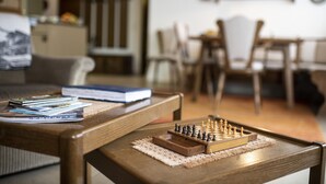 Une table basse en bois avec un jeu d’échecs et des magazines.