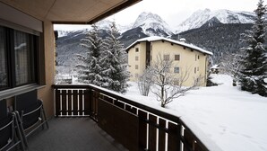 Un balcon avec vue sur des montagnes enneigées et un bâtiment.