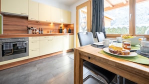 Eine moderne Küche mit Holzausstattung, einem eingebauten Ofen und einem Essbereich, gedeckt für das Frühstück.