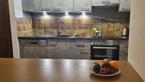 Cozinha com pia, fogão e forno. Há uma travessa de frutas na bancada.