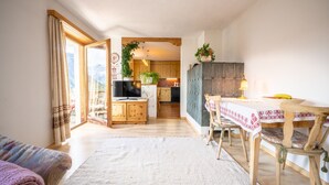 Ein gemütliches Wohnzimmer mit einer Couch, einem Esstisch mit Stühlen und einer Küche im Hintergrund.