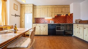 Eine kompakte Küche mit Holzausbau, einem eingebauten Backofen und einem Essbereich mit Tisch und Stühlen.