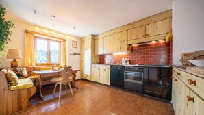 Eine gemütliche Küche mit Holzausbau, einer Ziegelrückwand und einem Essbereich mit Tisch und Stühlen.