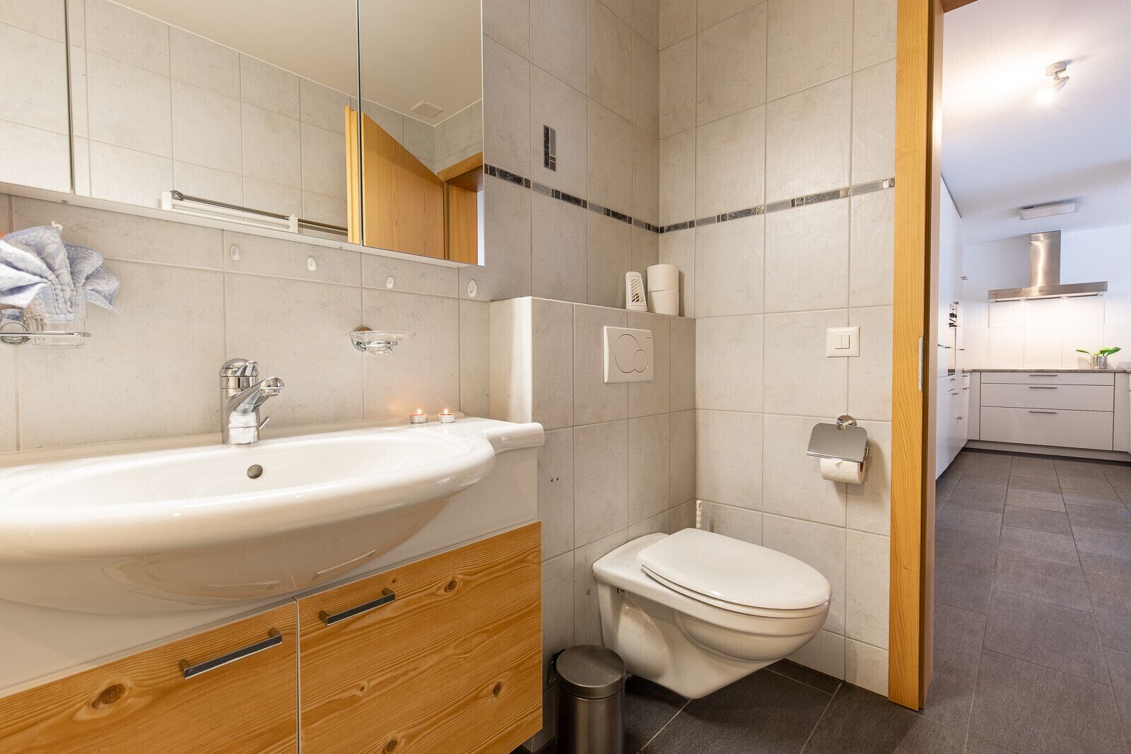 A modern bathroom with a large sink, toilet, and a mirror.