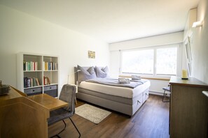 Een slaapkamer met een bed, bureau, boekenkast en raam.