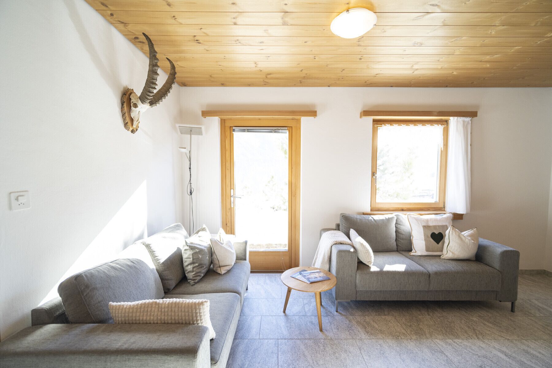 A living room with two grey sofas, a small wooden table, and a ceiling light.