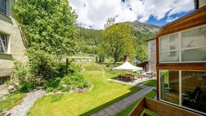 Ein gepflegter Garten mit einer Holzterrasse, einem Picknicktisch und einem weißen Zelt.