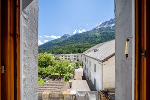 A view from a balcony overlooking a town with buildings and a mountain range in the background.