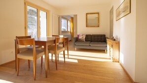 Un comedor con una mesa y sillas de madera, un sofá gris y un mueble pequeño.
