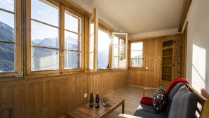 Ein Zimmer mit Holzwänden, großen Fenstern, einem Holztisch, einer Couch und einer Leiter.