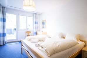 A hotel room with a bed, a bedside table, a lamp, and a window with curtains.