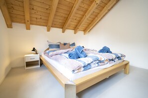 Ein Schlafzimmer mit einem hölzernen Bett, einem Nachttisch und einer schrägen Decke.