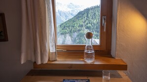 Une fenêtre donnant sur une chaîne de montagnes boisée.