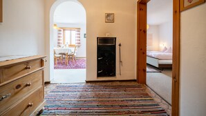 Ein Flur mit einem hölzernen Schminktisch, einem farbenfrohen Streifen Teppich, einem schwarzen Safe und einem Bett im angrenzenden Zimmer.