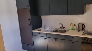 Eine moderne Küche mit dunklen Schränken, einem Edelstahlkühlschrank und einem Einbauofen.