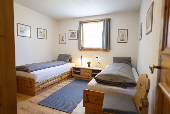 A bedroom with two wooden bunk beds, a desk with a lamp, and framed pictures on the wall.