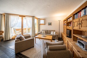 A living room with a sofa set, a coffee table, and a wooden bookshelf with books.