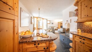 A kitchen with wooden cabinets, a granite countertop, and a dining area with a table and chairs.