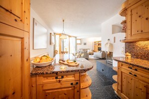 A kitchen with wooden cabinets, a granite countertop, and a dining area with a table and chairs.