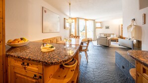 A kitchen with granite countertops, wooden cabinets, and a dining area with a table and chairs.