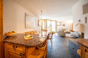 A modern kitchen with granite countertops, wooden cabinetry, and a dining area with a table and chairs.