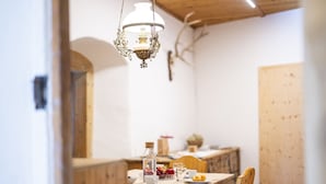 Un'area pranzo con un tavolo di legno apparecchiato per due, un lampadario e una panca di legno.