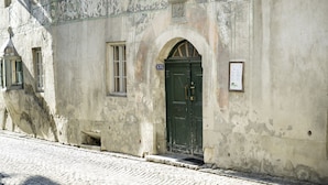 Un edificio storico con una porta verde, una piccola finestra e una targa.