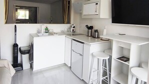 A compact kitchen with a microwave, sink, and bar stools. - Cap paradis (La Grande-Motte)