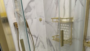 A glass-enclosed shower with marble tiles and gold fixtures. - Cap paradis (La Grande-Motte)