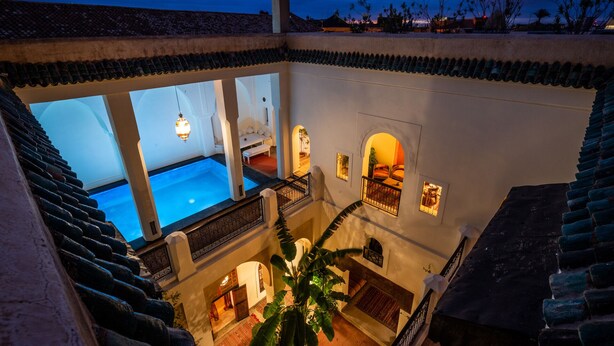 Un immeuble à plusieurs étages doté d’une piscine, de nombreux balcons et offrant une vue sur le coucher de soleil.