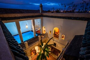 A multi-level building with a swimming pool, multiple balconies, and a view of the sunset. - Adilah - Luxury riad with swimming pool (Marrakech)