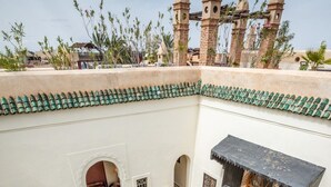 Une cour avec un bâtiment blanc, un balcon et une vue sur les environs.