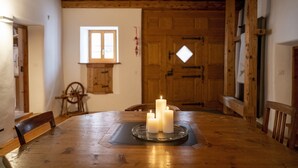 A wooden dining table with candles, a window, and a wooden door in the background. - Chasa Riatsch: Renovated Engadine house in the centre of Ardez (Ardez)