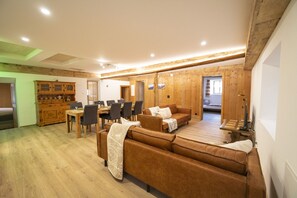 A wooden interior with a dining area, sofa, and a bed in the background.