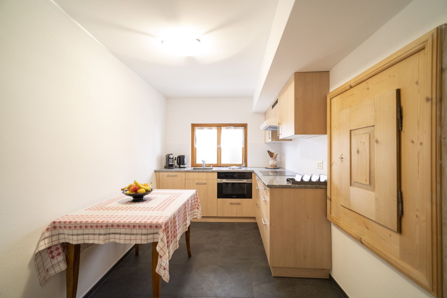 A compact kitchen with a dining table, a coffee maker, and a refrigerator.