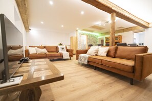 A modern living room with two brown leather sofas, a wooden coffee table, and a television.
