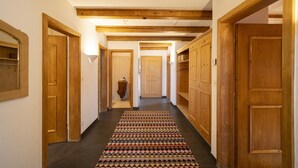 Een gang met houten deuren, een kamerbreed tapijt en een houten plafond.