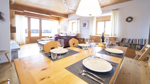 Een eethoek met een houten tafel voor vier personen, inclusief borden, glazen en bestek.