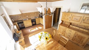 Una cocina con armarios de madera, una mesa de comedor con un jarrón de girasoles y una araña.