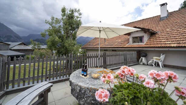 Un patio con una mesa de piedra, asientos exteriores y una valla de madera.