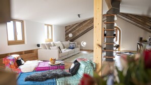 Un loft ampli amb un sostre alt, una escala de fusta, un sofà blanc i un sofà blau.