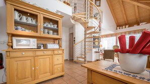 Eine Küche mit Holzausstattung, einer Mikrowelle und einem Toaster. Eine Wendeltreppe führt zu einer oberen Ebene.
