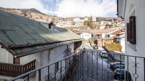 A balcony with a view of a town, including buildings and a mountain in the background.