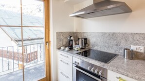 A kitchen with a stainless steel range hood, a built-in oven, a stovetop, and a coffee maker.