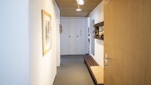 A hallway with a wooden ceiling, a bench, and a door with a chain lock. - Chasa Trü No. 7: Trü holiday settlement- Apartment No. 7 (Scuol)