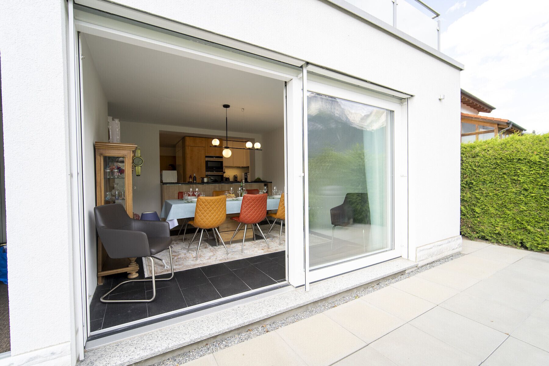 An open sliding glass door leading to a dining area with a kitchen in the background.